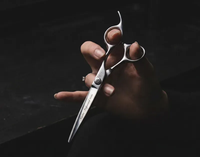 Hand holding scissors against a dark background