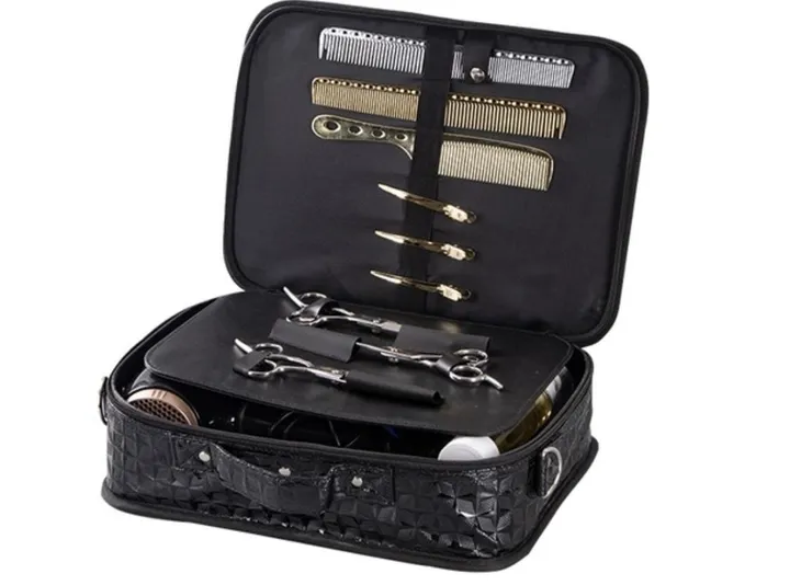 An open black scissor toolbox holding scissors in sleeves, combs and clips, with bulkier tools in the base.