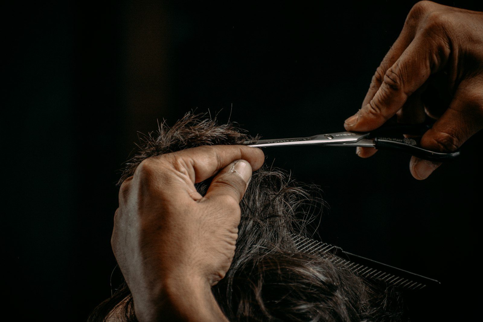 Stylist detailing a short haircut with compact scissors