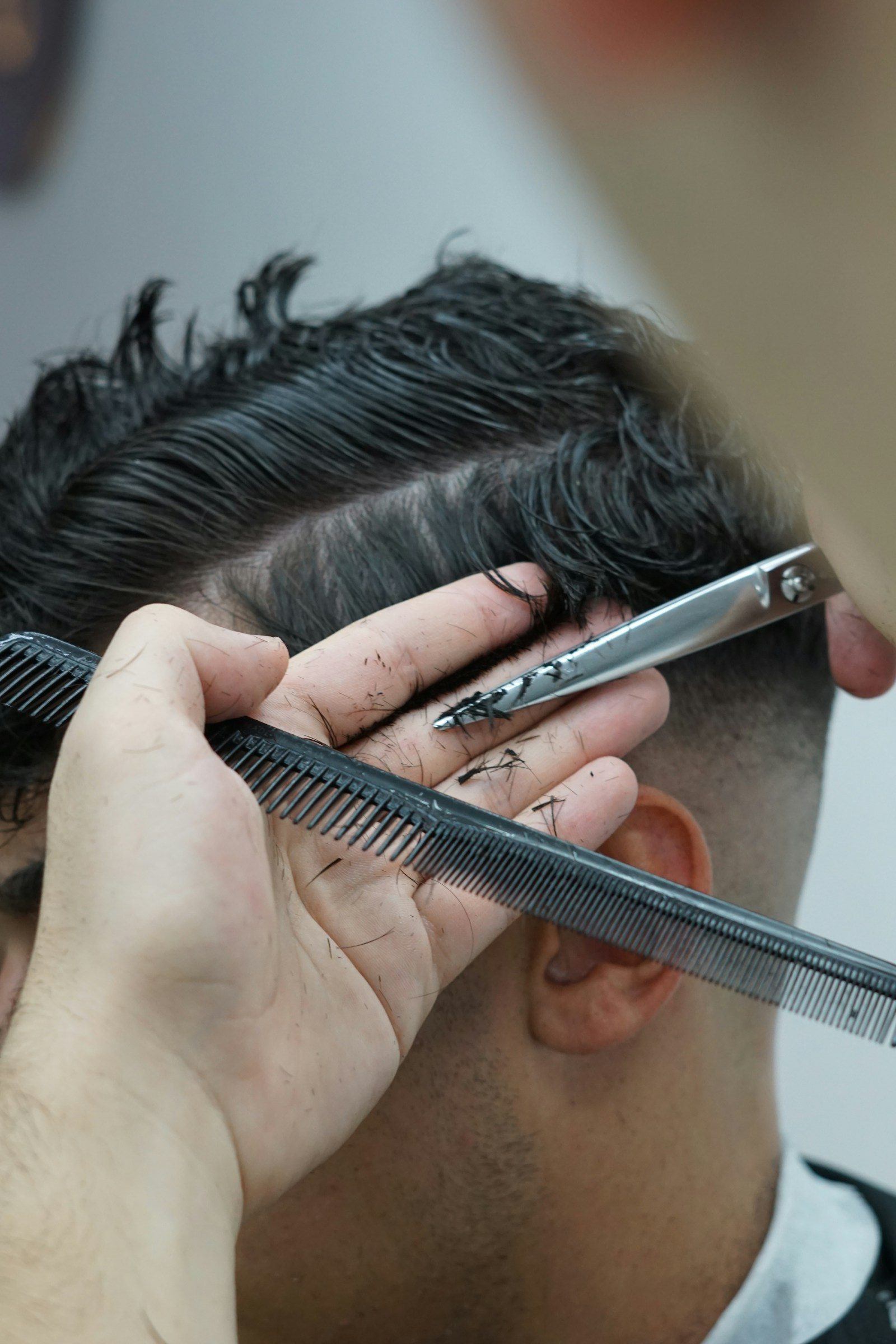 Detail shot of stylist cutting with comb and scissors